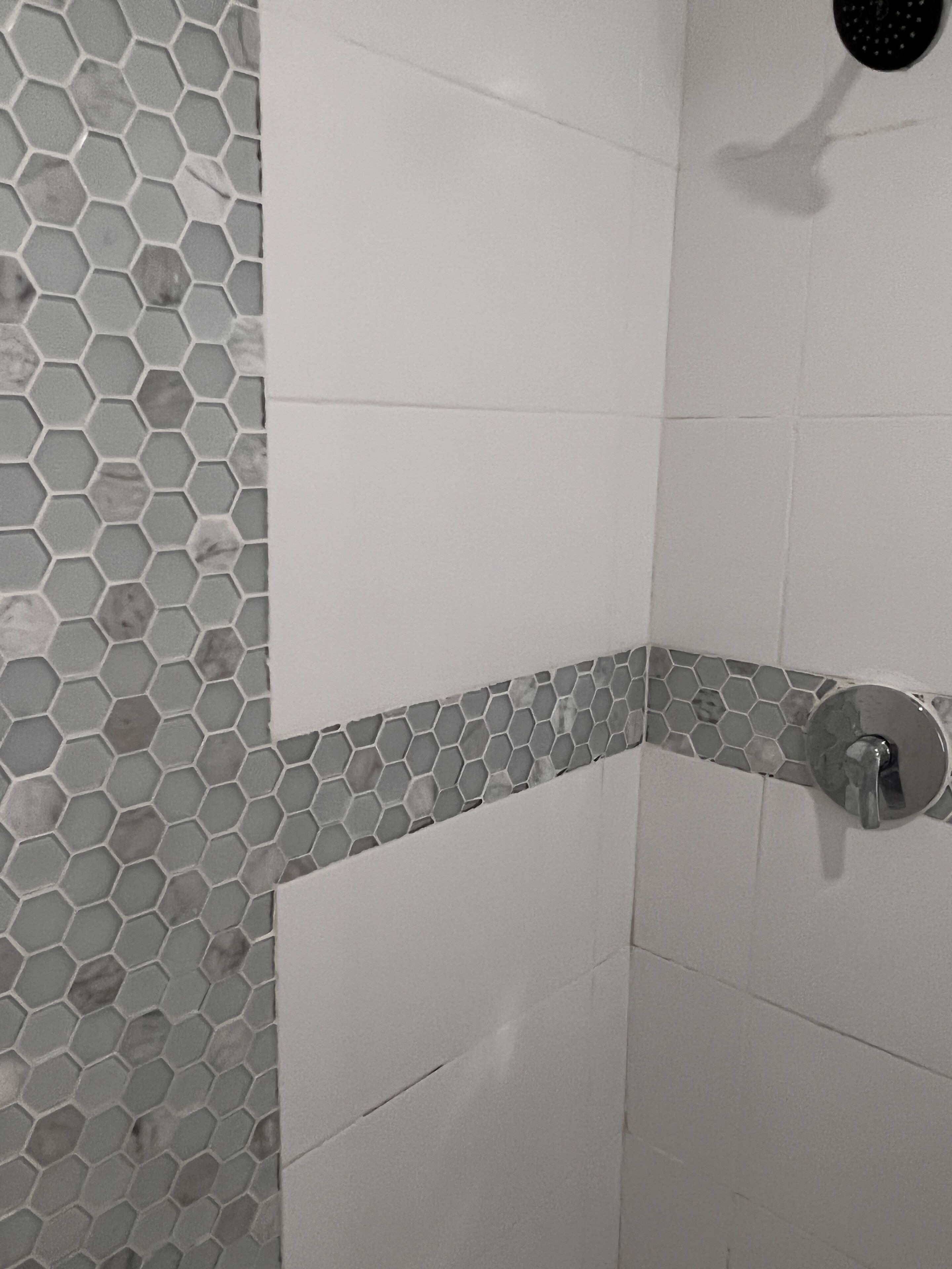 Un angolo doccia con motivi a esagono e un design a mosaico d'angolo.