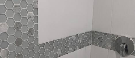 A shower area with hexagonal tile patterns and a corner tile design.