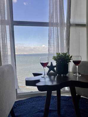 Un tavolo con due bicchieri da vino e una decorazione a stella, vicino a una finestra con vista su un corpo d'acqua.