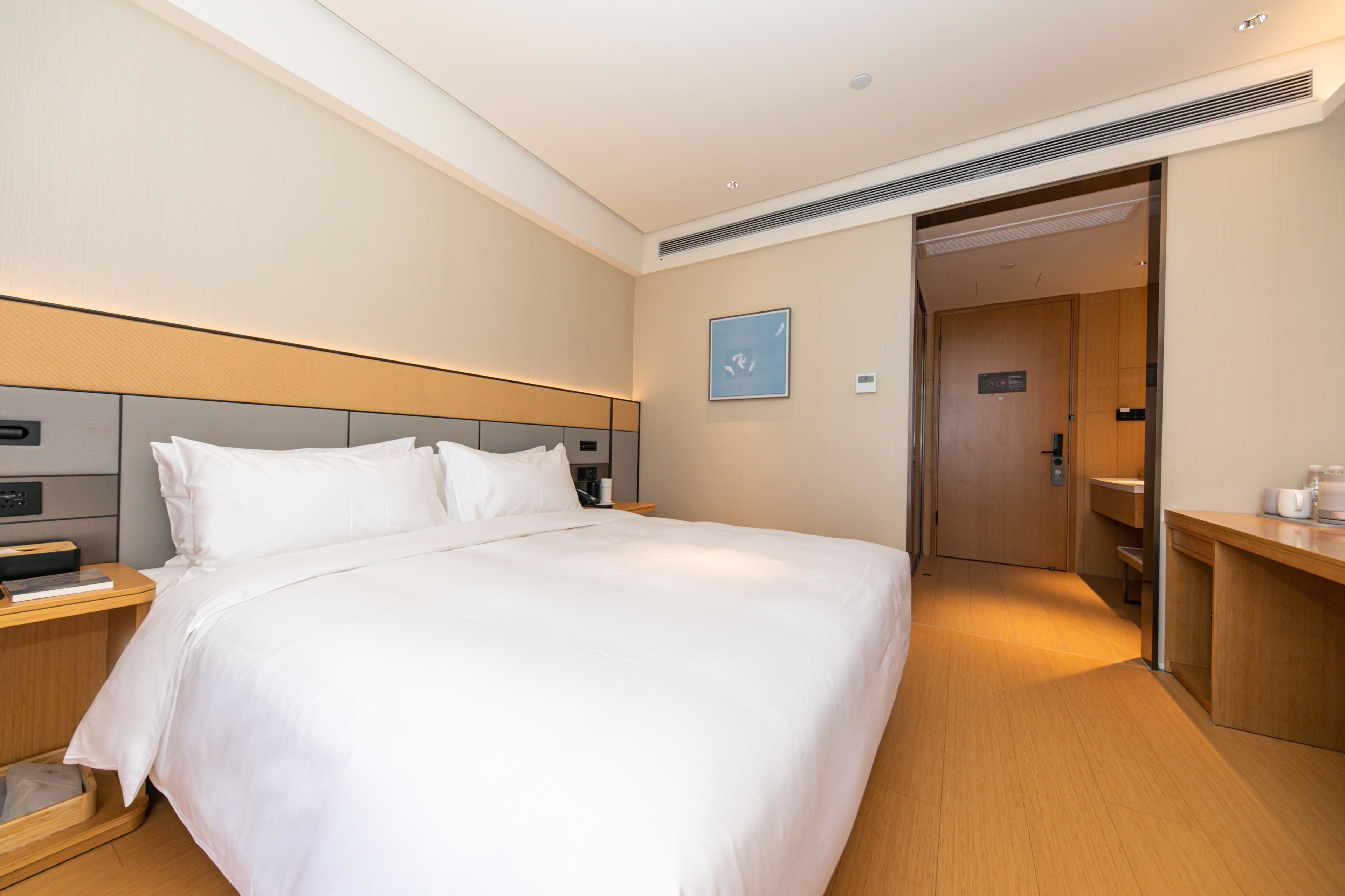 Una habitación de hotel con una cama grande, mesitas de noche, un escritorio y una puerta que da a un baño.