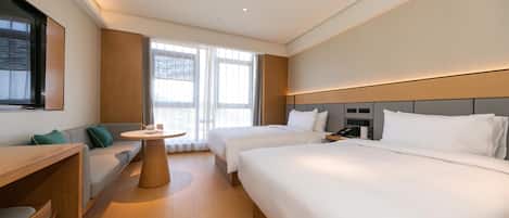 Une chambre d’hôtel avec deux lits, un bureau, une chaise et une petite table.