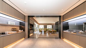 Un hall d’hôtel moderne avec un espace salon central, un comptoir d’accueil et un grand miroir sur l’un des murs.