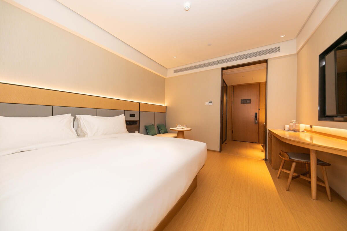 A hotel room with a large bed, a desk, and a television.