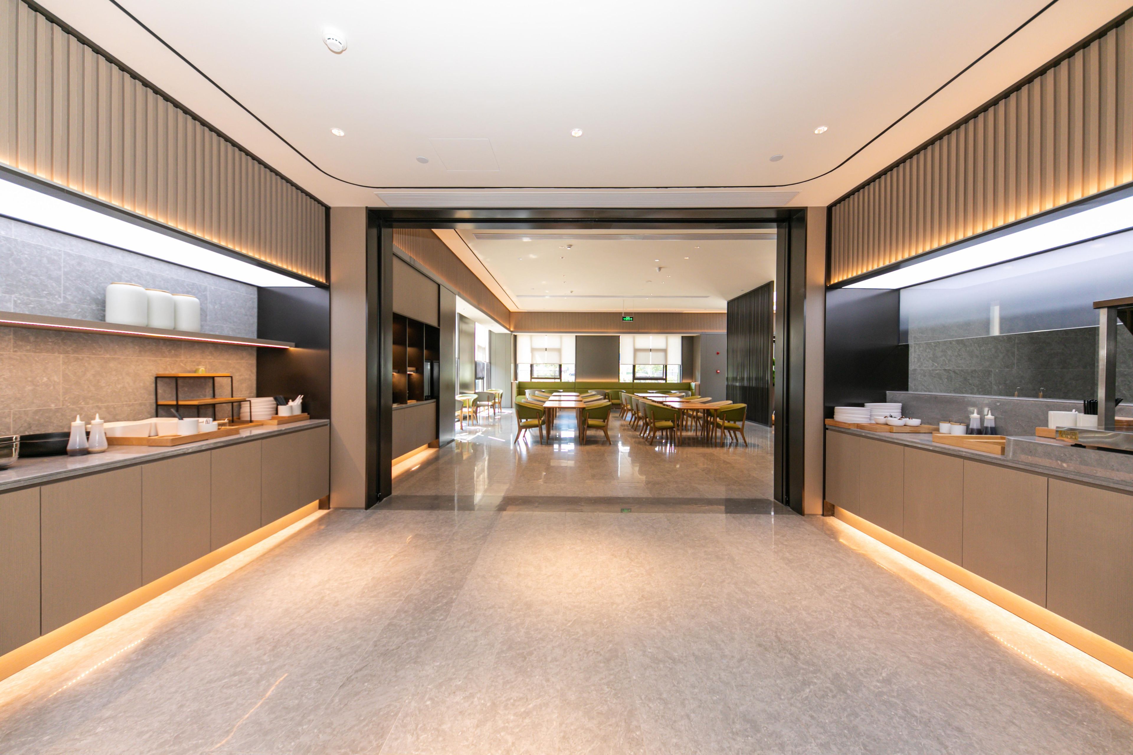 Een moderne hotellobby met een centraal zitgedeelte, een receptiebalie en een grote spiegel aan de muur.