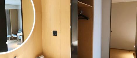 Une salle de bain moderne avec un grand miroir, un lavabo blanc et un meuble-lavabo en bois.