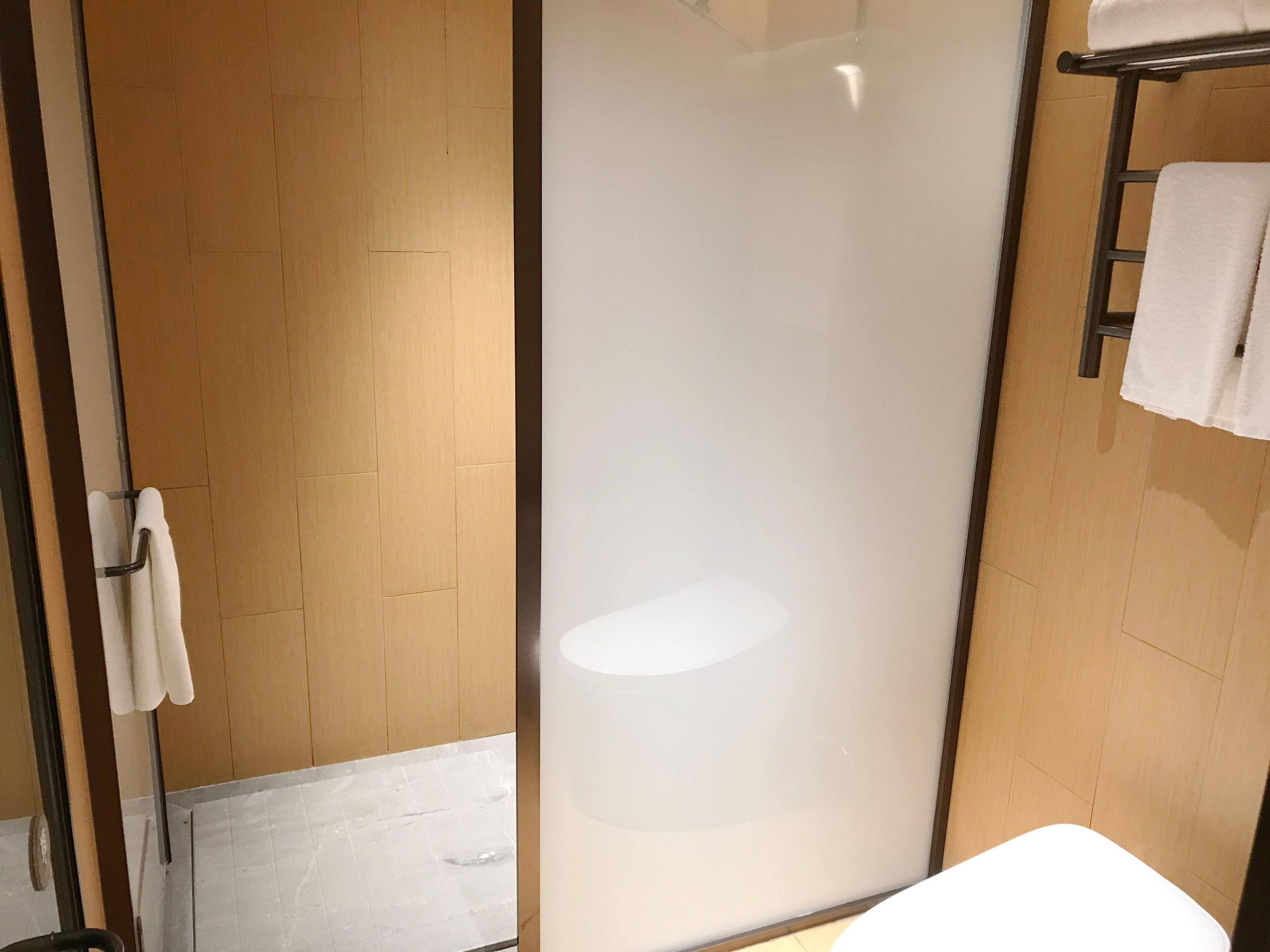 Un bagno moderno con box doccia in vetro, lavandino bianco e porta asciugamani.