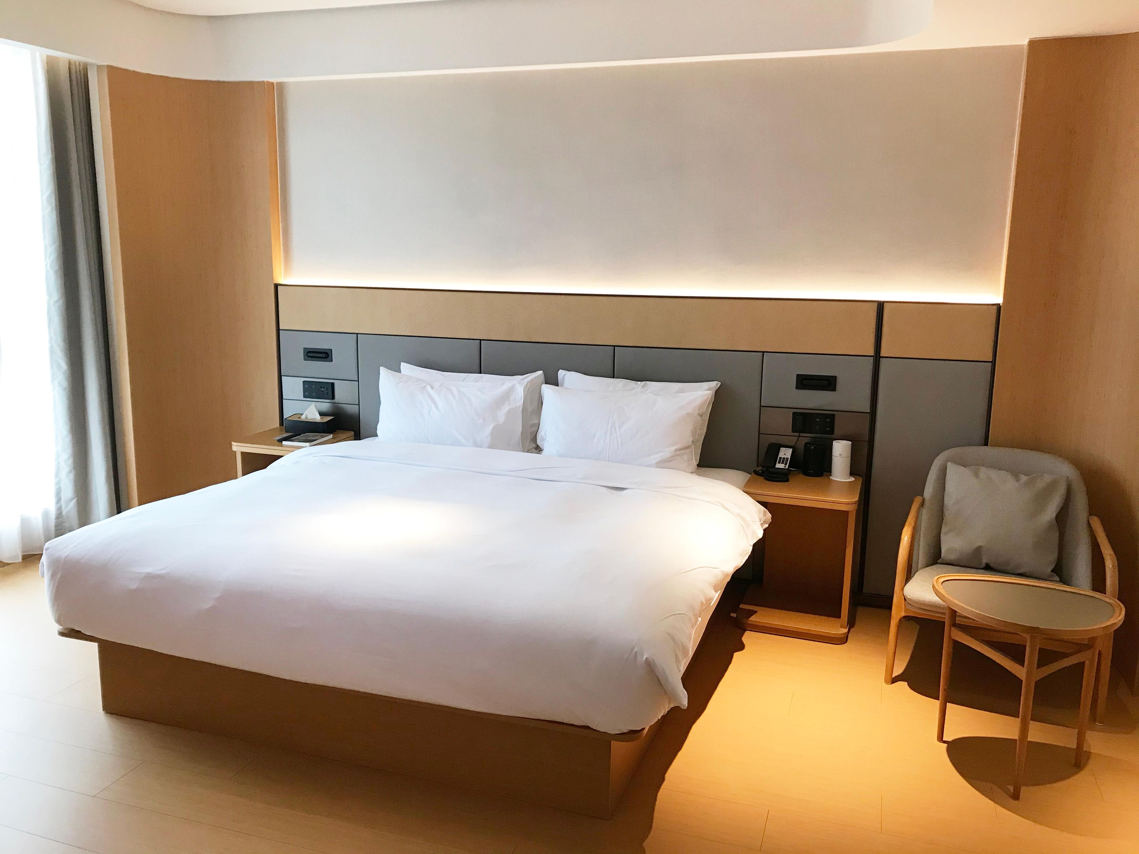 Een hotelkamer met een groot bed, nachtkastjes, een stoel en een bureau.