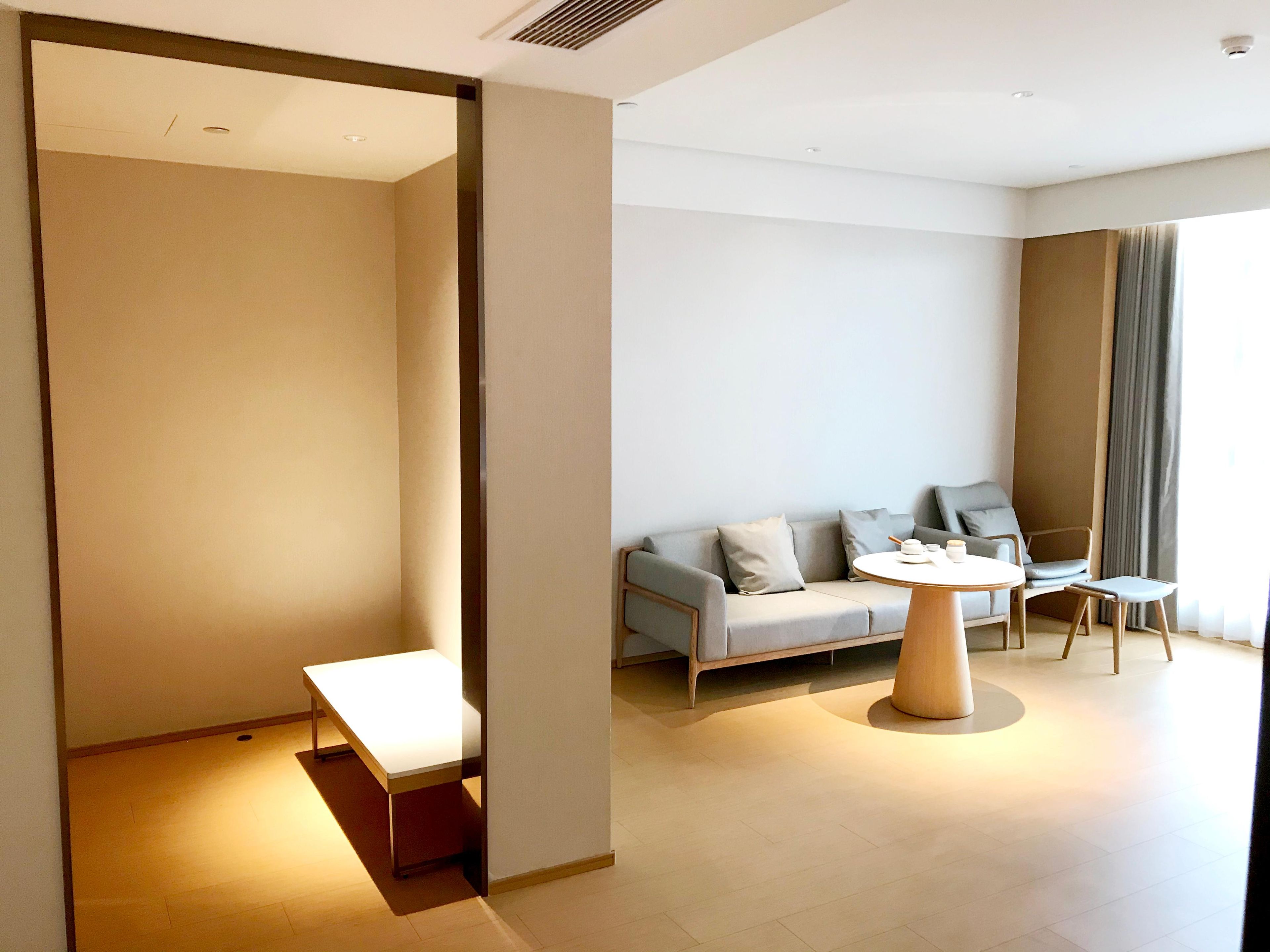 A modern hotel room with a sofa, a round table, and a small table.