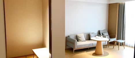 A modern hotel room with a sofa, a round table, and a small table.