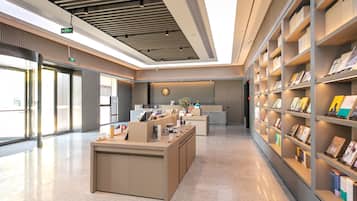 A modern reception area with a reception desk, a digital display, and a bookshelf with books.