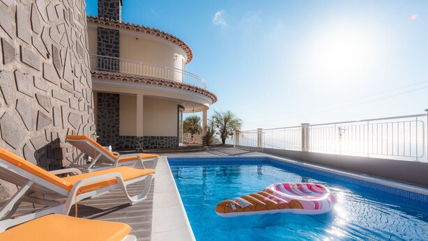 A poolside area with lounge chairs and a floating ring. - Sunnyside Villa with private pool - 10 min from the beach! (Calheta)