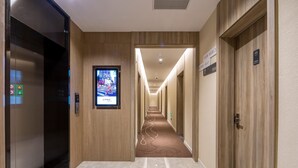 A hotel hallway with an elevator, a digital display, and a carpeted floor. - Hanting Shanghai Lujiazui Oriental Pearl (Shanghai)