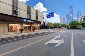 Un hôtel à la façade moderne, avec un ciel dégagé et une vue sur la ville en arrière-plan.