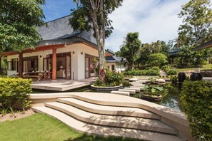 Una casa moderna con un porche cubierto, un estanque de carpas y un jardín cuidado.
