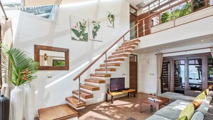 A spacious living area with a wooden staircase, a large sofa, a coffee table, and a TV. - TED Villas (Koh Samui)