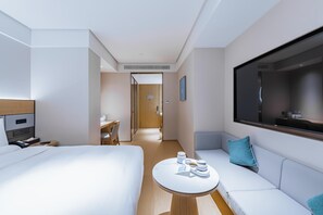 A modern hotel room with a bed, a sofa, a small table, and a TV. - JI Hotel (Shanghai)