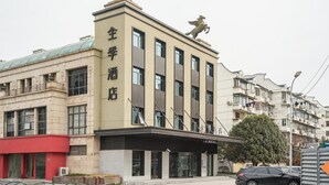 A hotel with a prominent sign, a modern facade, and two statues on the roof. - JI Hotel (Shanghai)