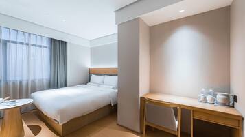 A hotel room with a bed, a desk, a chair, and a round table.