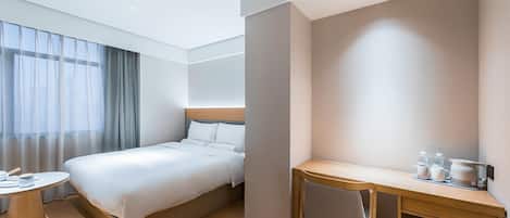Une chambre d’hôtel avec un lit, un bureau, une chaise et une table ronde.