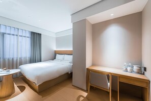 A hotel room with a bed, a desk, a chair, and a round table. - JI Hotel (Shanghai)