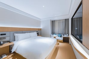 Habitació d'hotel amb llit, tauleta de nit, làmpada i finestra amb cortines.