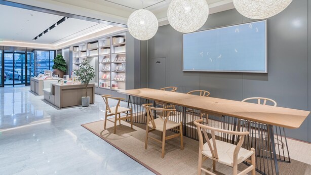 A modern library with a long wooden table, chairs, bookshelves, and large spherical chandeliers. - JI Hotel (Shanghai)