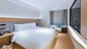 A hotel room with a bed, bedside table, lamp, and a window with curtains. - JI Hotel (Shanghai)