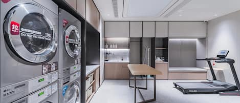 Een moderne hotelkamer met een wasruimte, een kleine kitchenette, een tafel en een loopband.