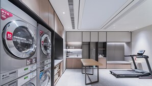 A modern hotel room with a laundry area, a small kitchenette, a table, and a treadmill. - JI Hotel (Shanghai)