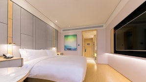 Habitación de hotel con una cama grande, mesitas de noche, un escritorio, un televisor de pantalla plana y un cuadro en la pared.