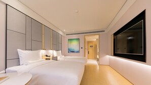 Una habitación de hotel moderna con una cama grande, mesitas de noche, un televisor de pantalla plana y un cuadro en la pared.