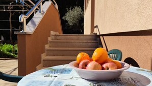 Een tafel met een schaal fruit, een stoel en een trap die naar een deur leidt.