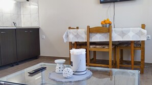 Een moderne keuken met donkere kastjes, een glazen tafel en een eethoek met een houten stoel en tafel.