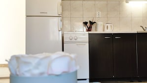 Een keuken met een witte koelkast, een fornuis en donkere keukenkastjes.