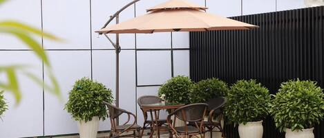 Un patio exterior con una mesa y sillas, rodeado de plantas en macetas.