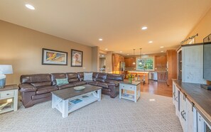 A living room with a brown leather sofa, a coffee table, and a kitchen in the background.