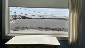 A view through a window of a parking lot with a building labeled "DWOODS" in the background. - Rio Motel and Suites (Wildwood)