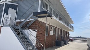 A two-story building with a balcony and a stairwell. - Rio Motel and Suites (Wildwood)