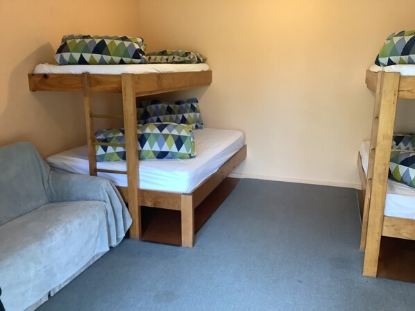 A bunk bed room with a grey sofa and patterned pillows. - Glenmark Holiday Park (Fairview)