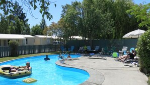 Uma piscina com espreguiçadeiras e boias.