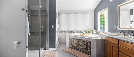 A modern bathroom with a glass shower enclosure, a vanity with a decorative tile backsplash, and a large mirror.