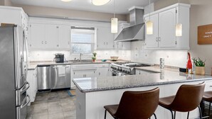 A modern kitchen with white cabinets, stainless steel appliances, and a central island with bar stools. - Lake front with dock and boat ramp (Waverly)