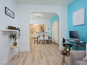 A modern living room with a dining area, a kitchen in the background, and a blue accent wall. - Trendy Bungalow mins to Colleges & Downtown Gainesville (Gainesville)