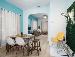Ein modernes Wohnzimmer mit Essbereich, ausgestattet mit einer Couch, einem Couchtisch und einem gelben Sessel.