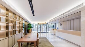 A modern hotel lobby with a long reception desk, a turnstile entrance, and a large potted plant. - Ji Hotel Hangzhou South Railway Station (Hangzhou)
