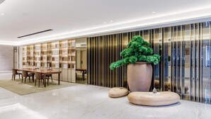 A modern interior with a dining area, a large potted plant, and a decorative wall. - Ji Hotel Hangzhou South Railway Station (Hangzhou)