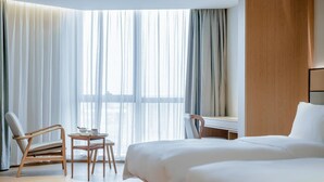 A hotel room with a bed, a desk, a chair, and a small table with a teapot. - Ji Hotel Hangzhou South Railway Station (Hangzhou)