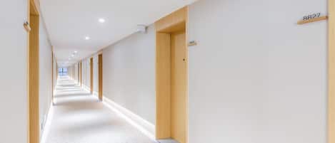 A long, narrow hotel corridor with wooden doors and a carpeted floor.