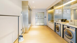 A modern hotel room with a hallway leading to a door, a vacuum cleaner, and a washing machine. - Ji Hotel Hangzhou South Railway Station (Hangzhou)