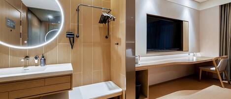 A modern bathroom with a large mirror, dual sinks, a vanity, and a shower area.